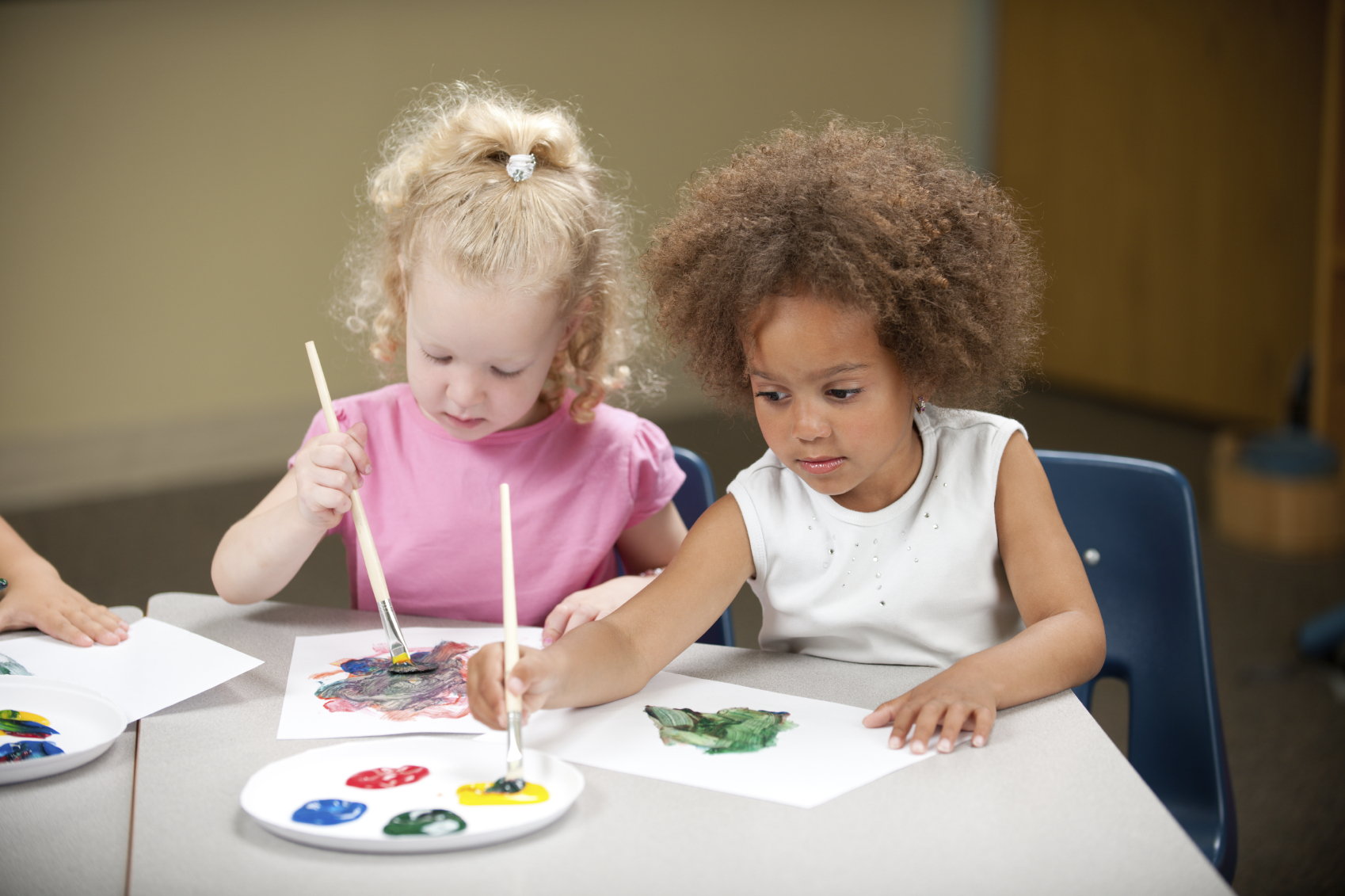 Preschool kids painting in a classroom.